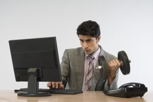 Businessman exercising with dumbbells and getting fit at work